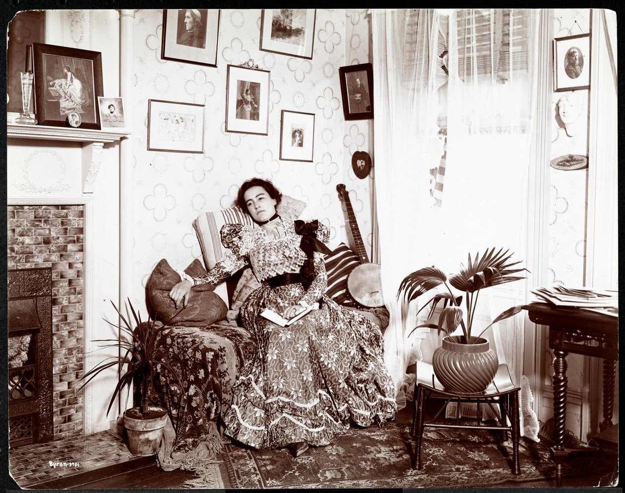 Eine Frau, die in einem Stuhl liegt und ein Buch liest, 1896-98 von Byron Company