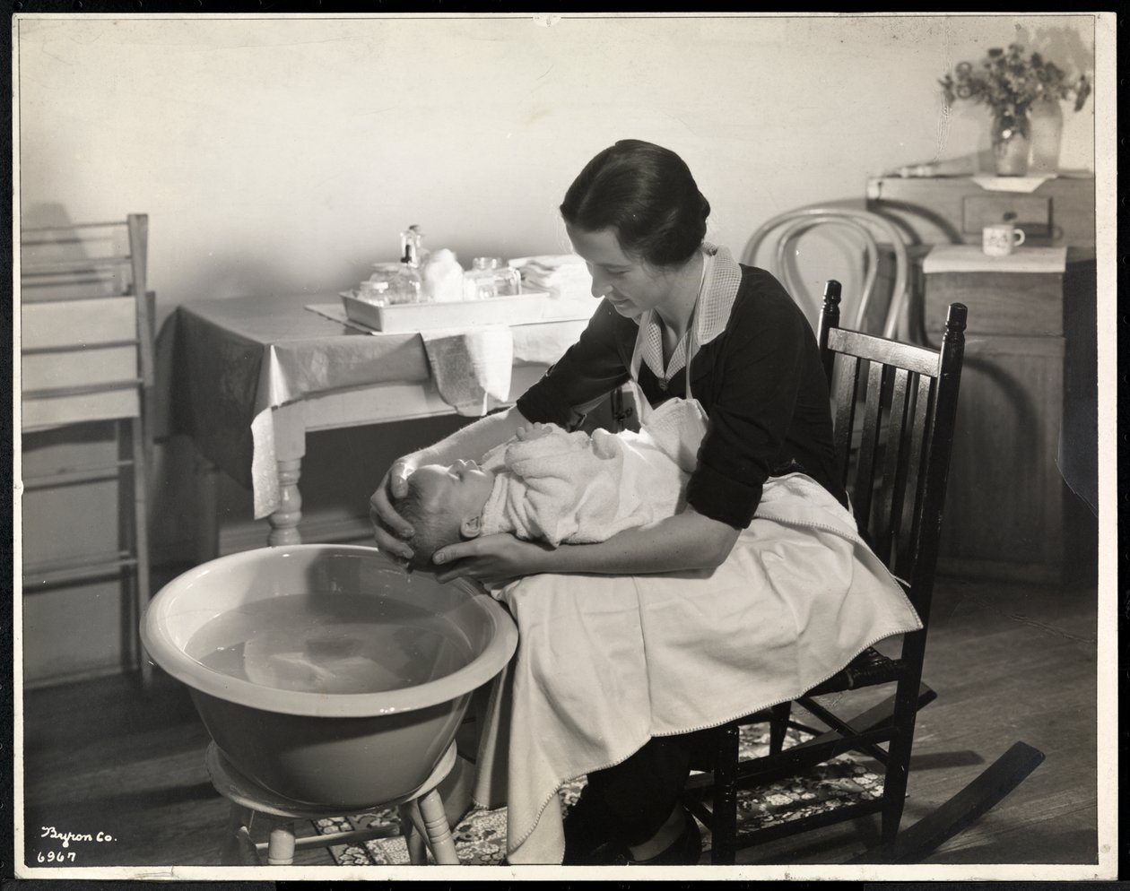 Eine Frau wäscht den Kopf eines Babys im Maternity Center Association in der 211 East 57th Street, New York, 1934 von Byron Company