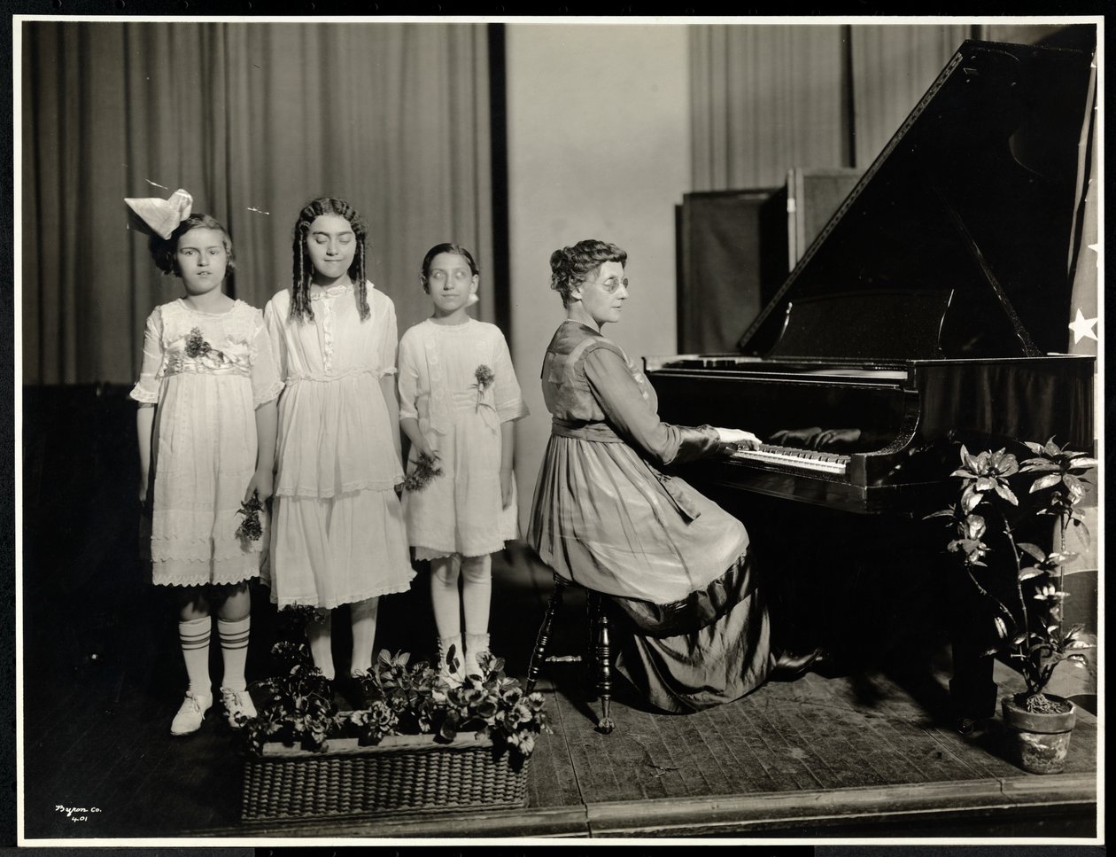 Frau spielt Klavier, während drei Mädchen im New York Association for the Blind singen, 111 East 59th Street, New York, ca. 1917 von Byron Company