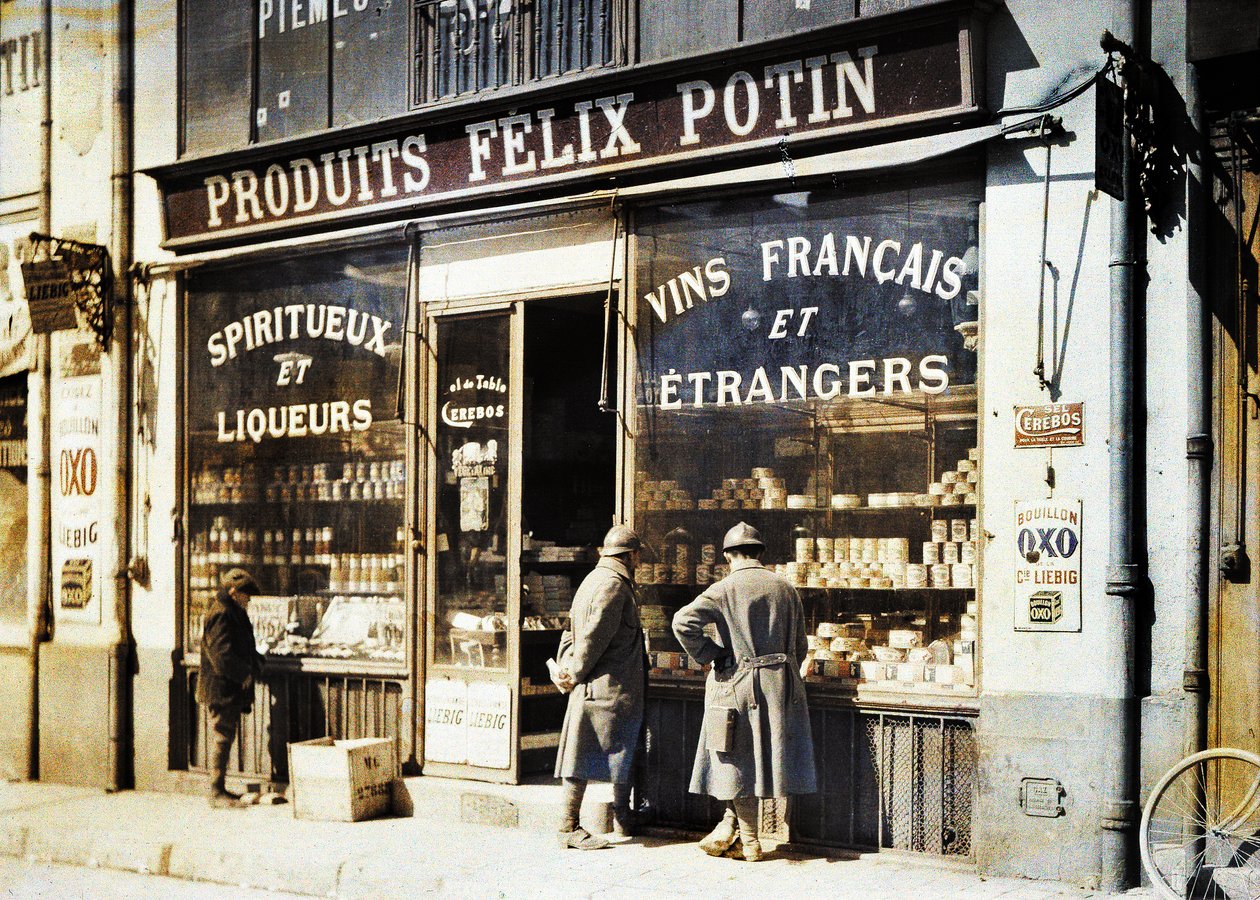 Zwei französische Soldaten und ein Junge vor dem Spirituosengeschäft Felix Potin auf dem Markt, Reims, Marne, Frankreich, 1917 von Fernand Cuville