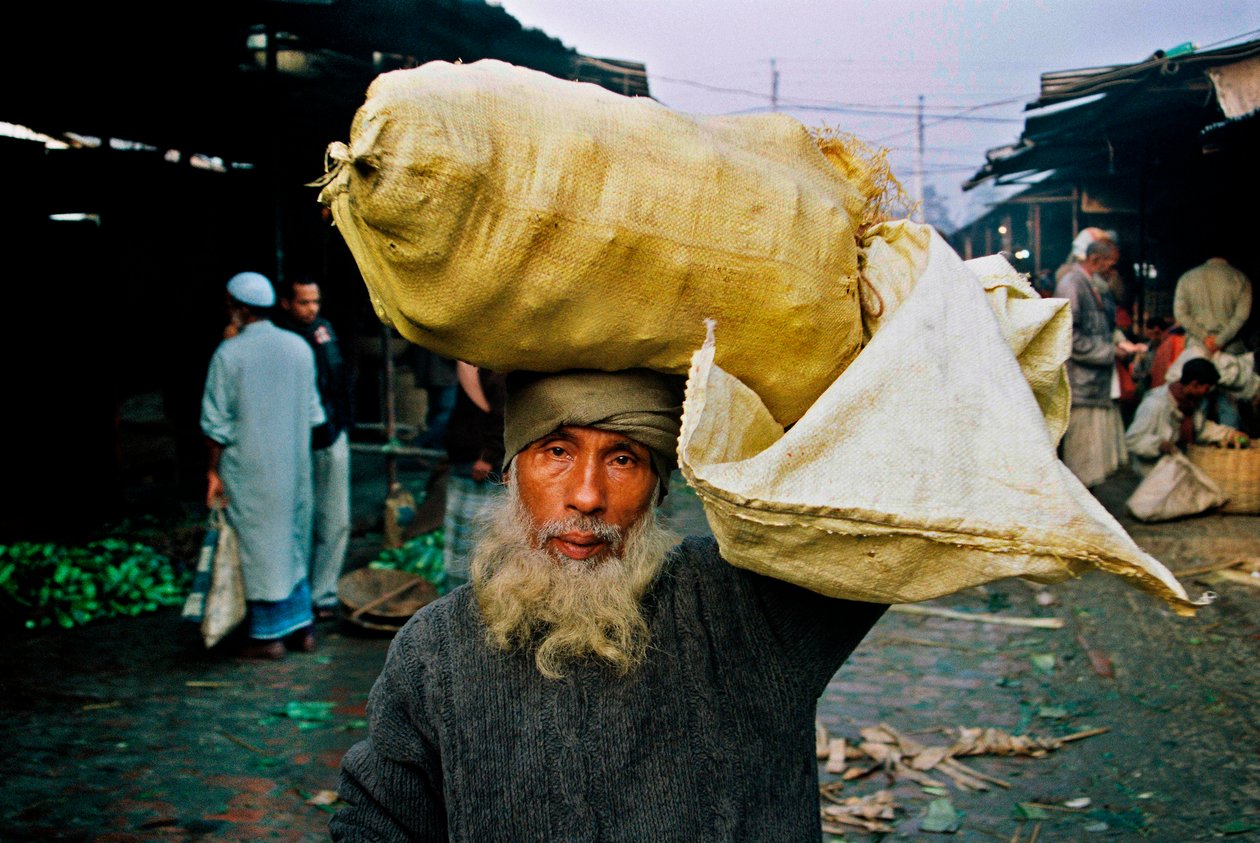 Porträt eines Gemüsehändlers. Abdus Samad kauft Gemüse auf dem Großmarkt und verkauft sie auf der Straße. Nirala Kacha Bazar, Khulna, Bangladesch. von Unbekannt Unbekannt